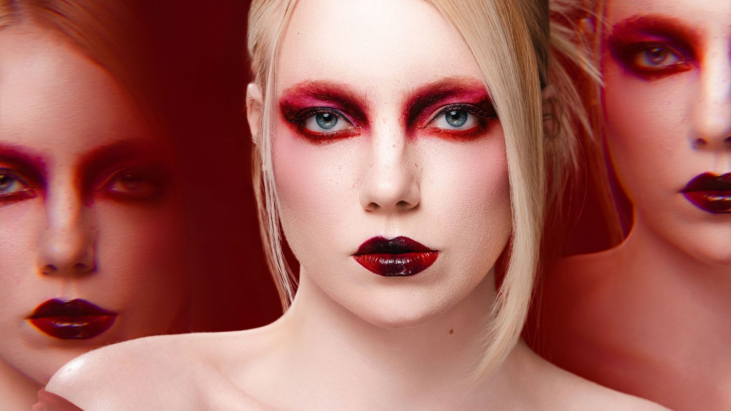 Three women with dramatic red and black makeup, bold dark lips, and blue eyes against a red background.