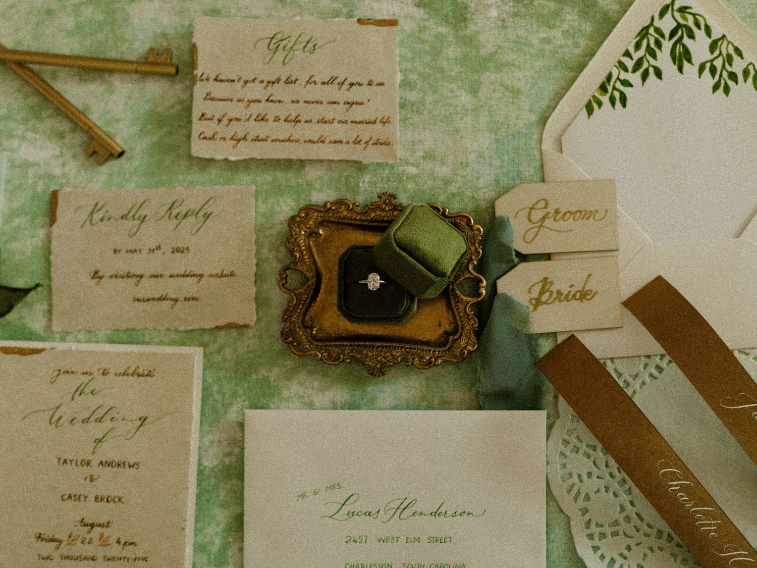 Vintage wedding invitation suite with handwritten calligraphy and botanical elements on green background.