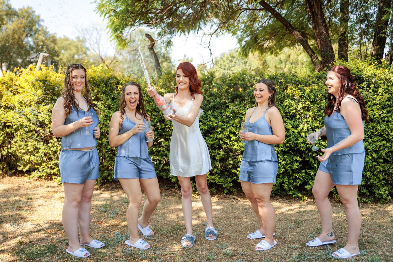 Bridesmaids in light blue dresses posing casually outdoors.
