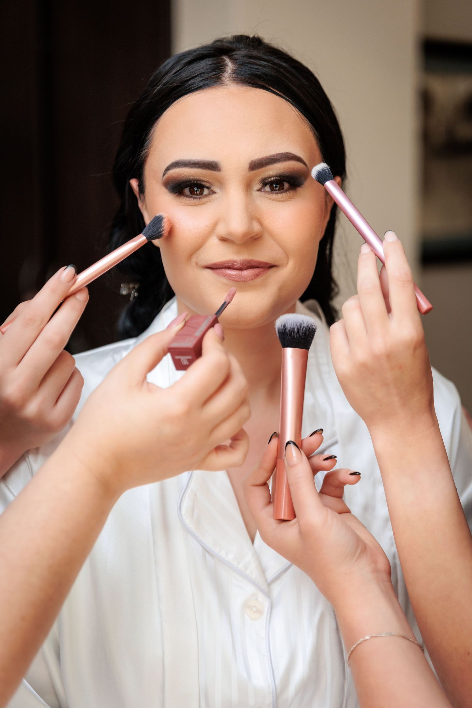 Step by step makeup application process showing brushes and cosmetics being applied.