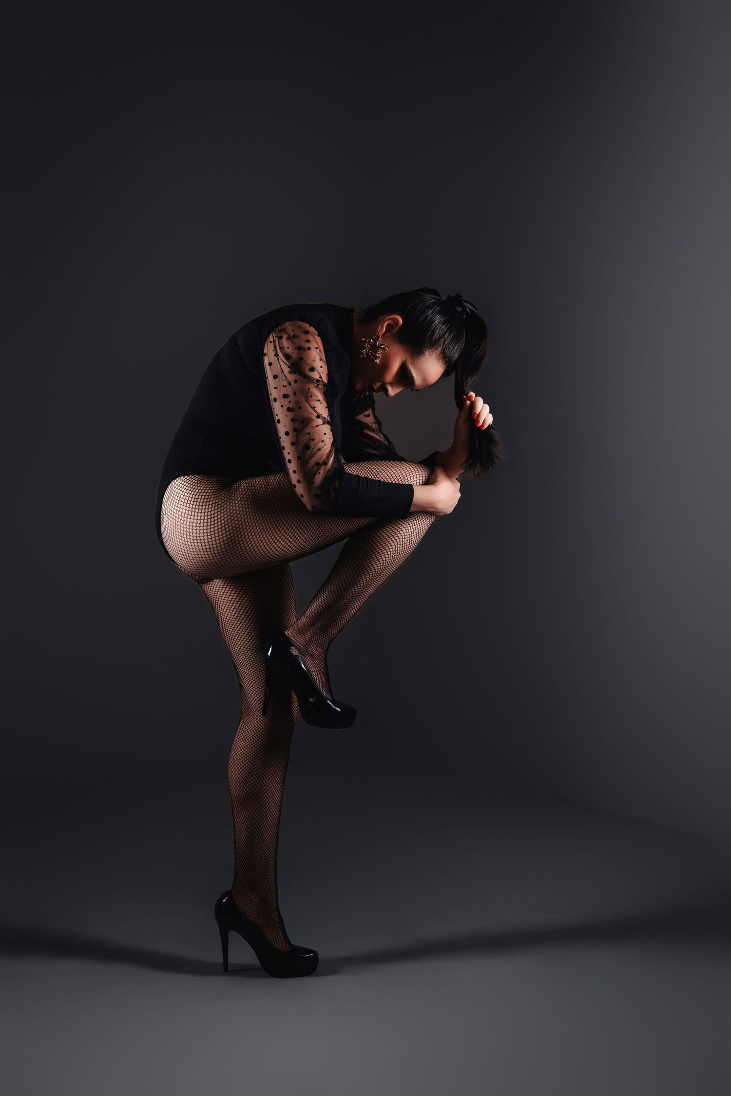Artistic silhouette of a dancer in black attire striking dynamic poses against a dark studio backdrop.