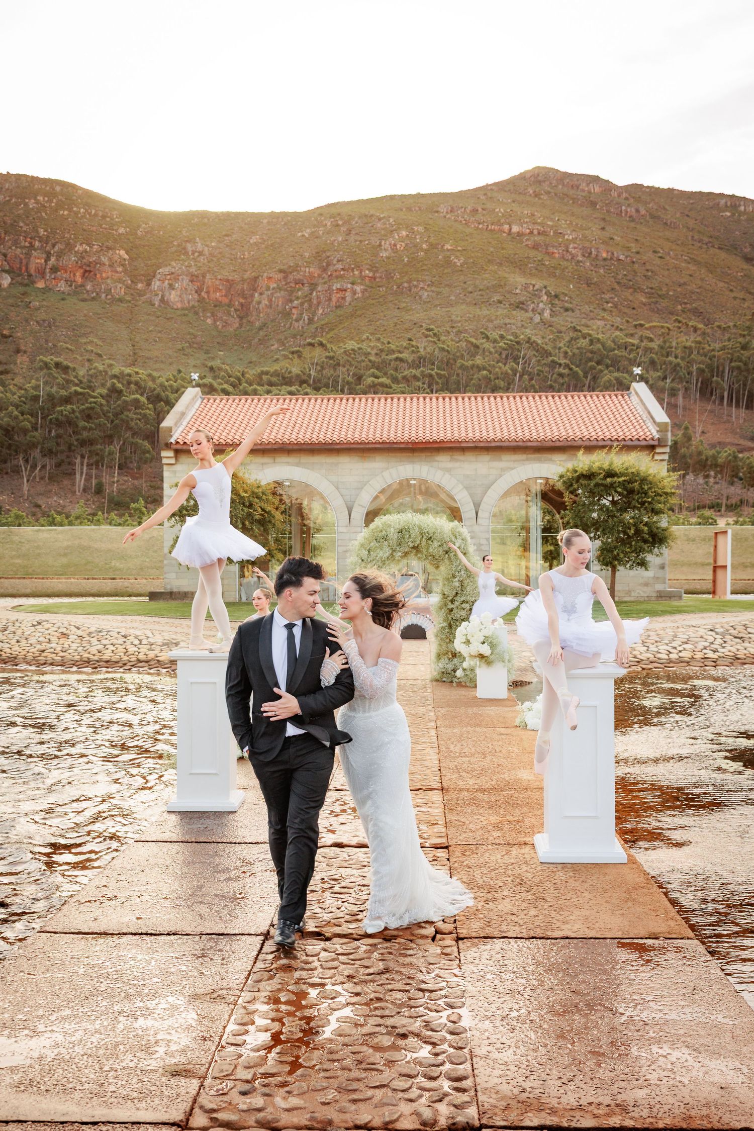A romantic outdoor wedding ceremony setup with white decor elements and mountain views in the background.