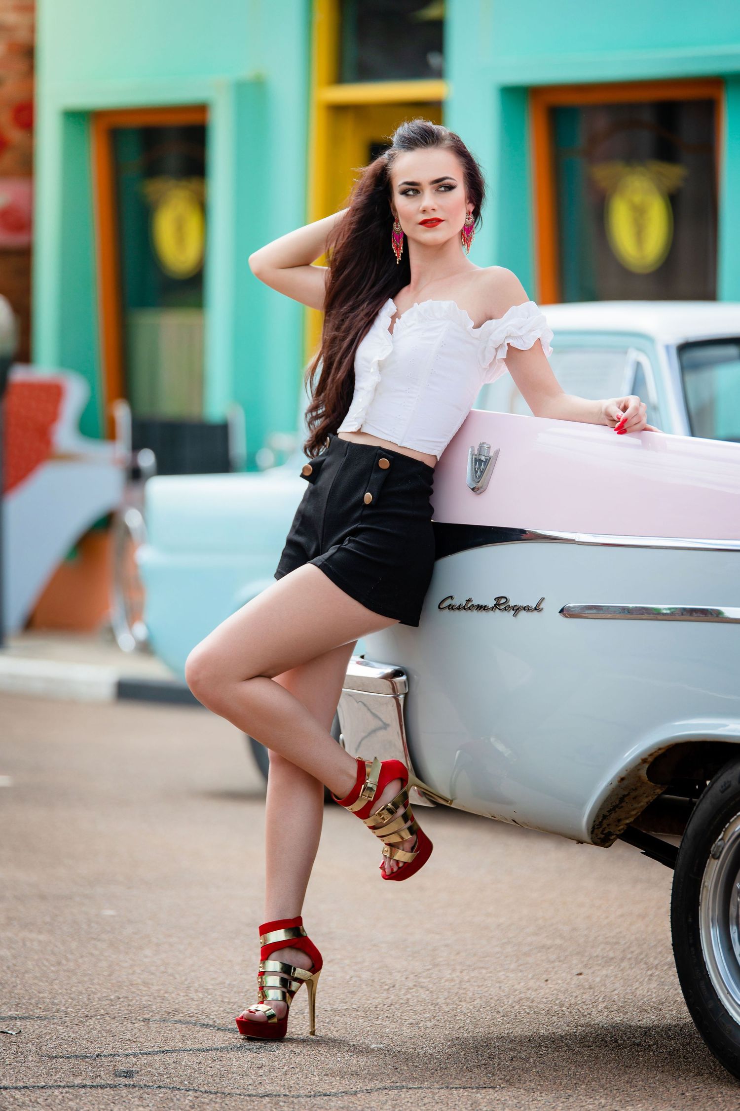 A vintage-inspired photoshoot featuring a classic pink and silver car with retro styling elements.