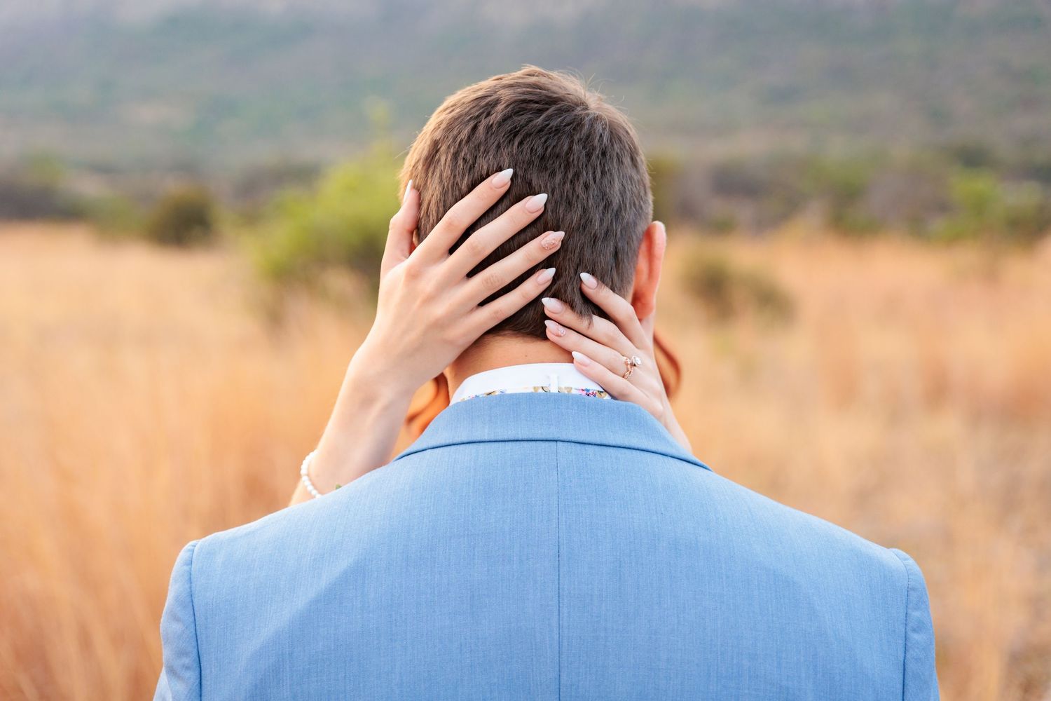 Light blue suit details against sunset landscape background.