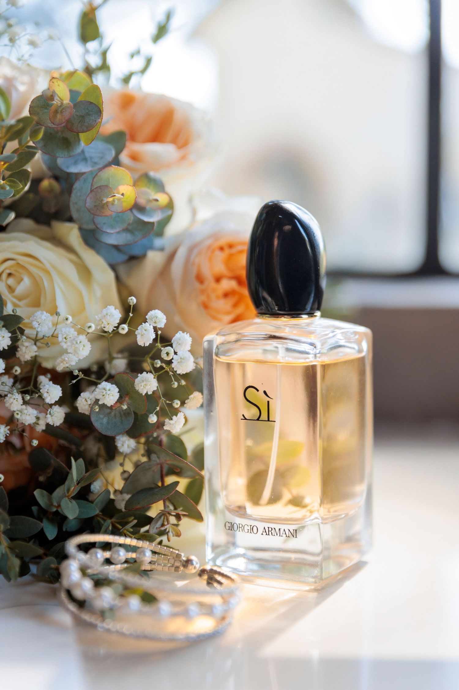 Elegant perfume bottles displayed with soft floral arrangements and baby's breath.