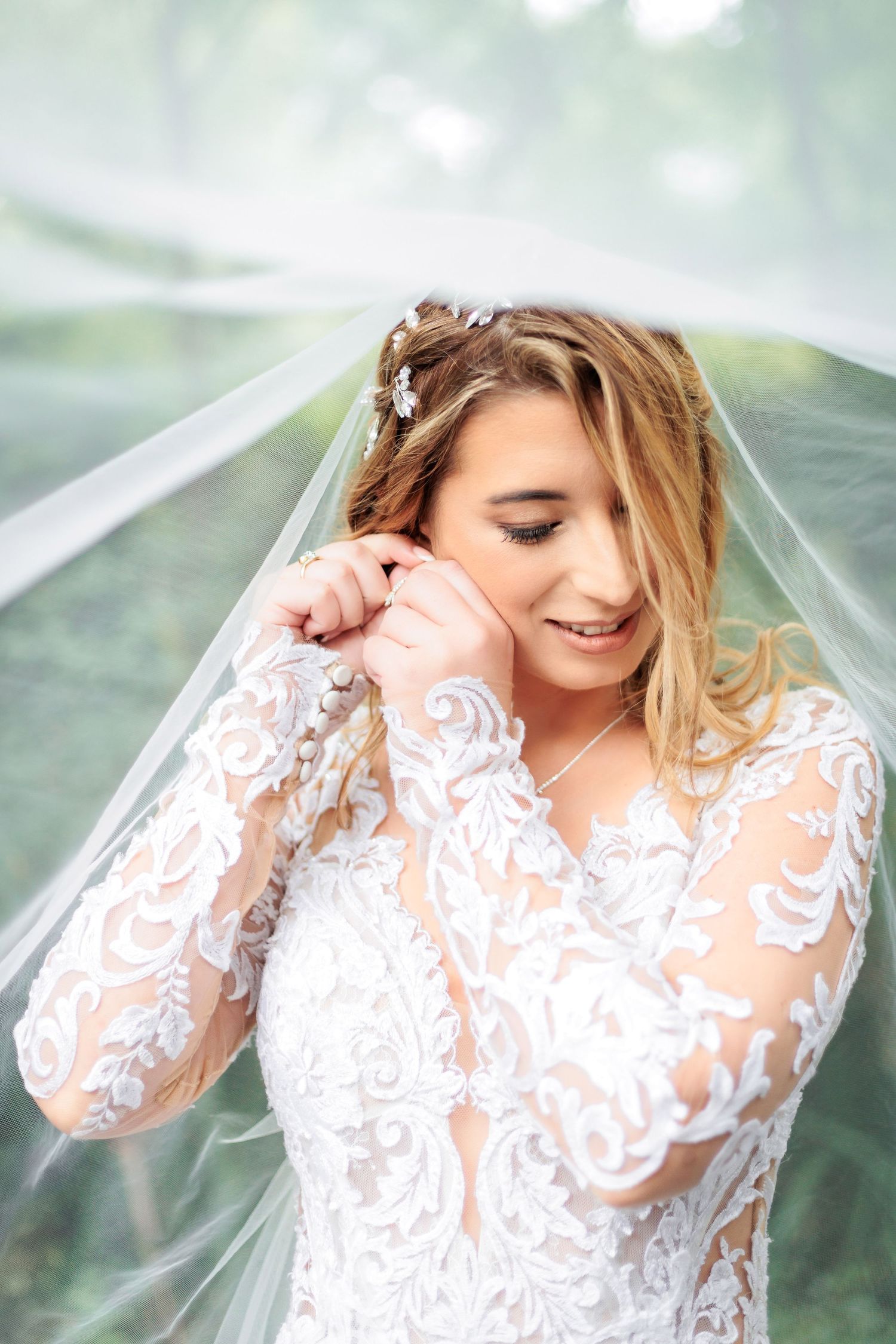 Romantic bridal photos with flowing veil and lace long-sleeve dress in natural lighting.