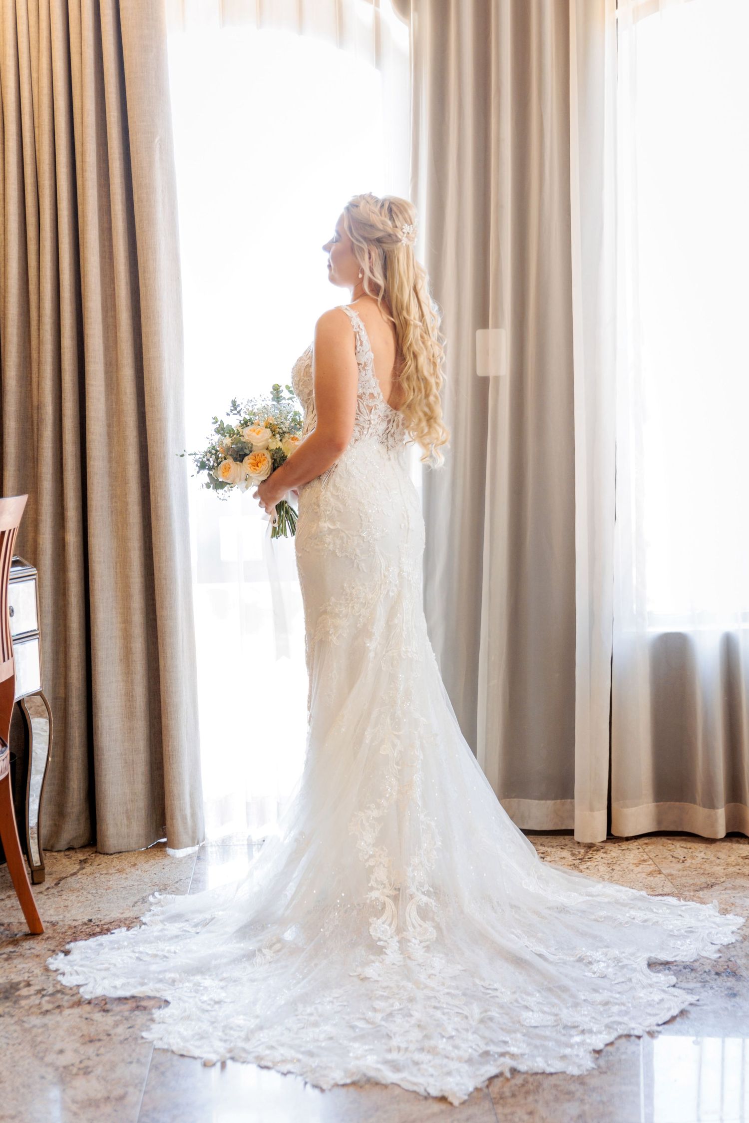 Elegant white wedding dress with lace details and flowing train photographed in natural light.
