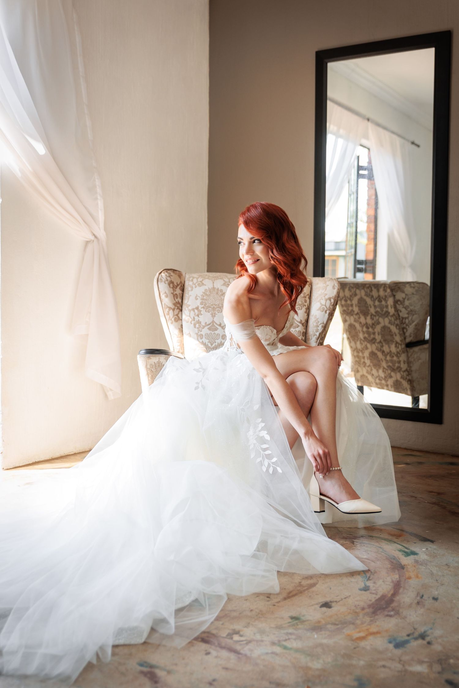 White wedding dress with flowing tulle skirt in an elegant indoor setting.
