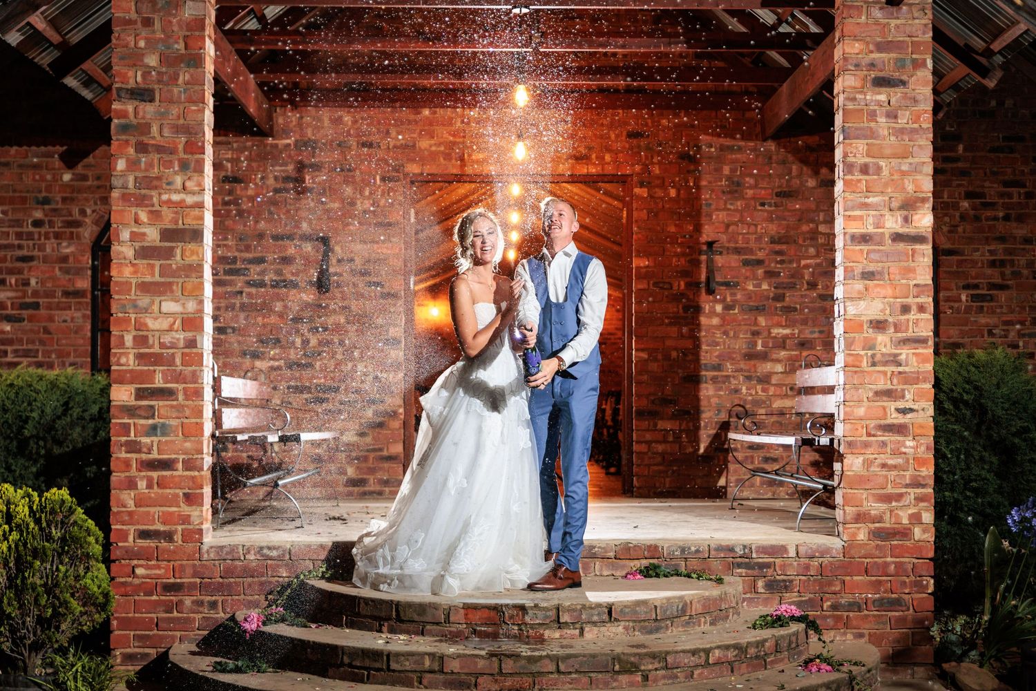 A couple poses against rustic brick archways in an outdoor venue during a romantic wedding photoshoot.