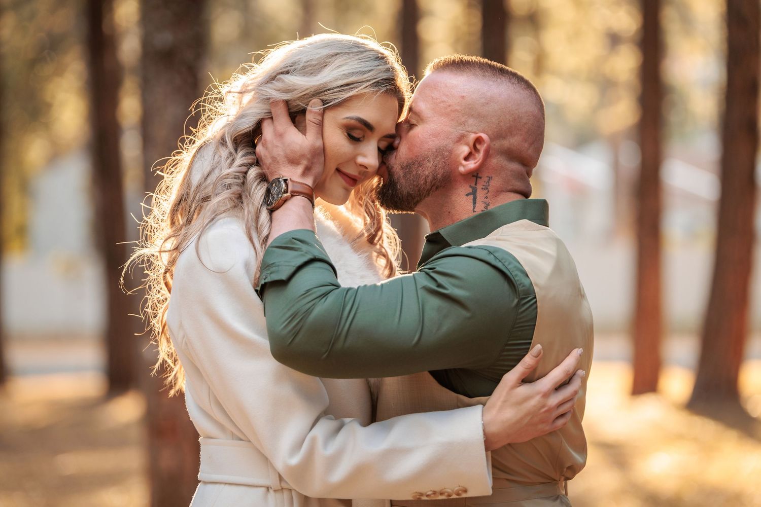 A couple shares romantic moments in a sunlit forest setting during a golden hour engagement photoshoot.