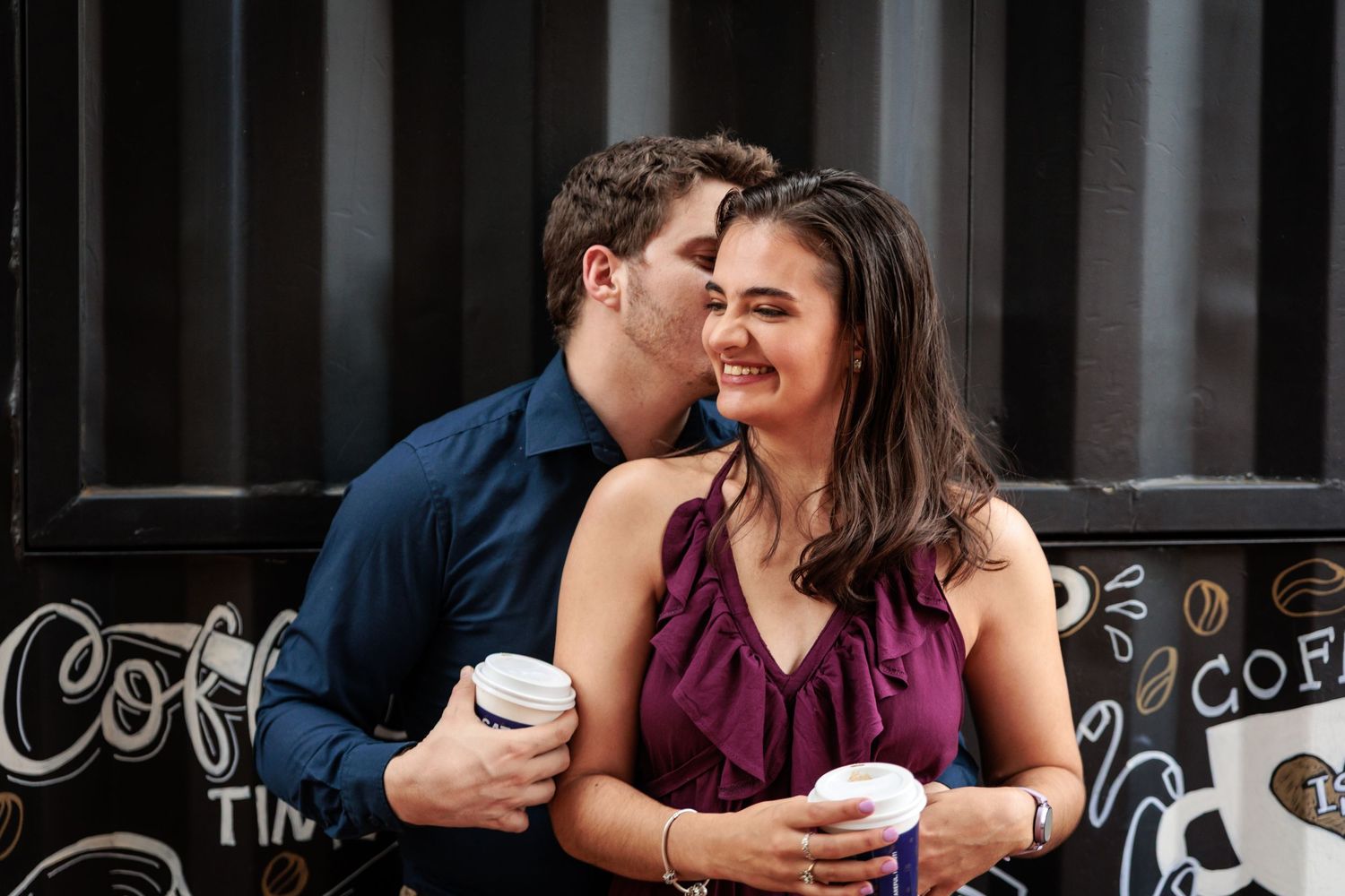 Couple sharing intimate moments and coffee while sitting at a cafe counter.