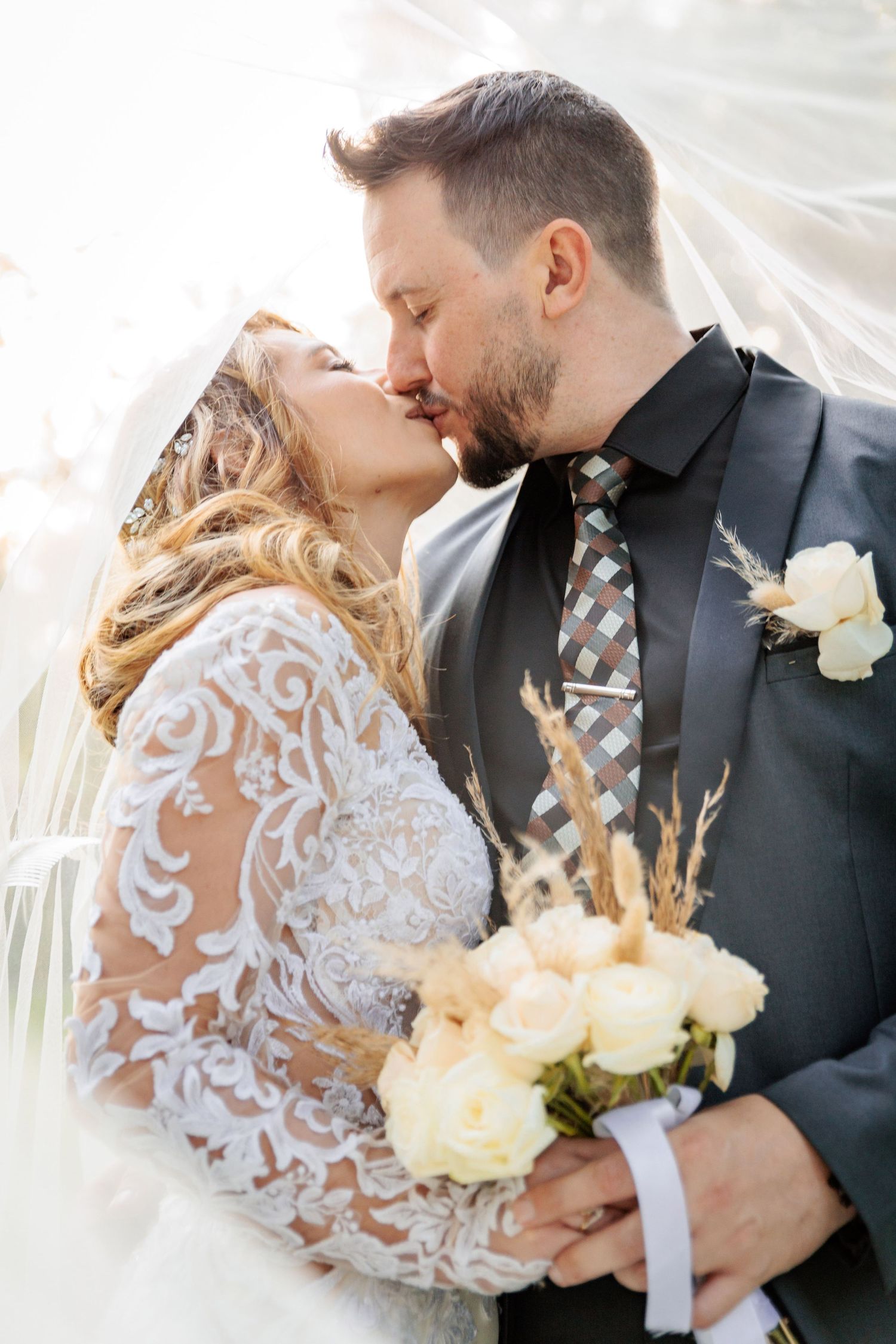 Intimate wedding portrait showing delicate lace details and white roses against natural light.