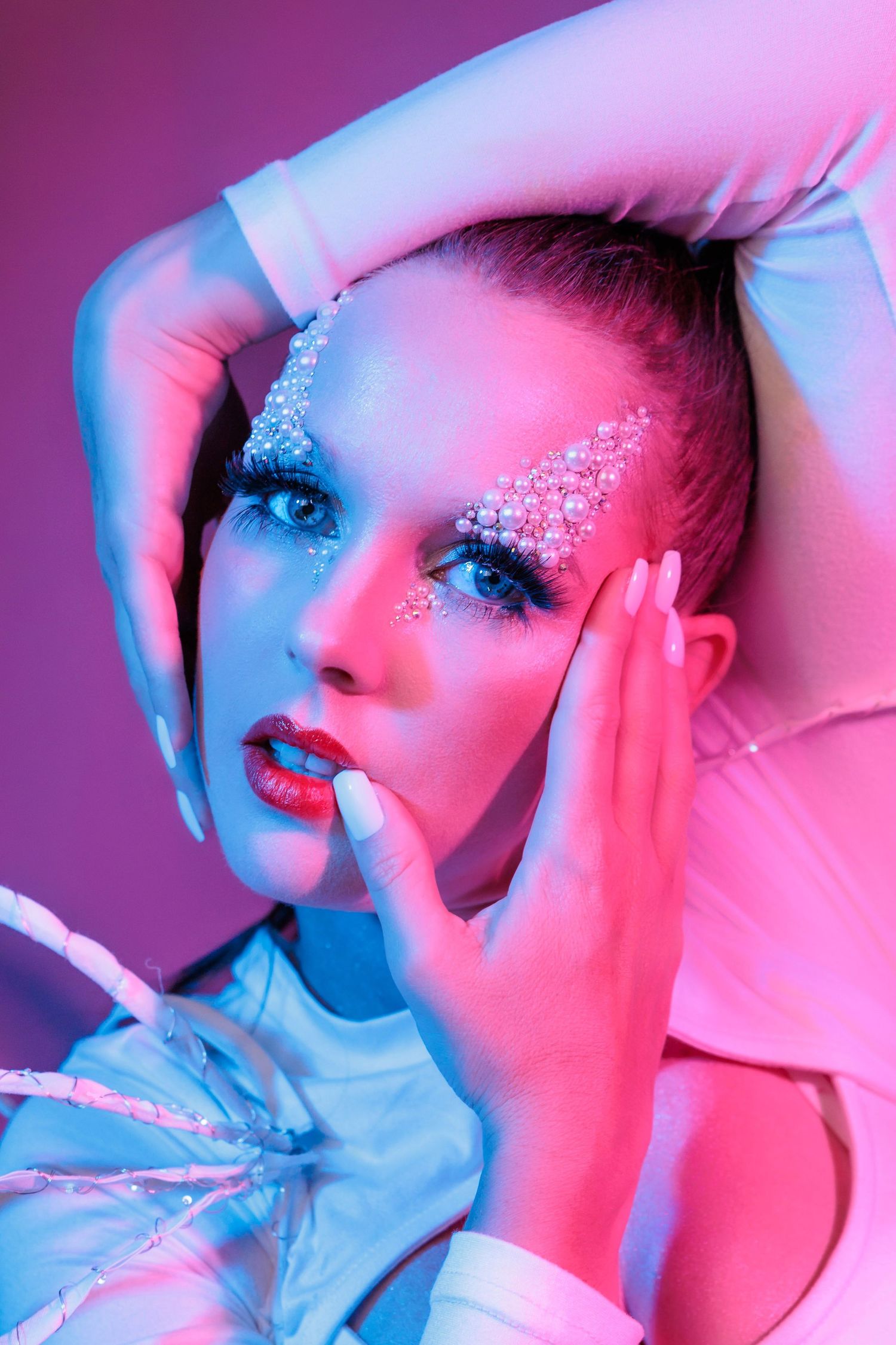 Artistic beauty portrait with pink and blue lighting showing glitter makeup and dramatic poses in a photo series.
