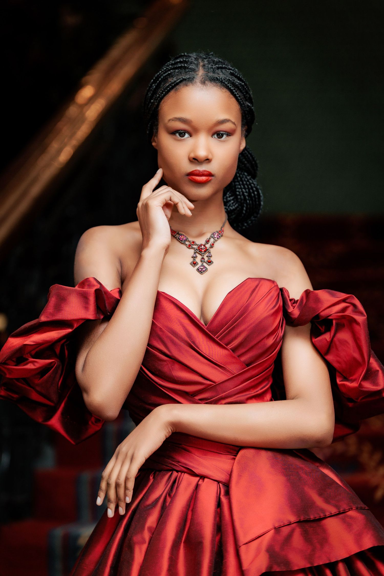 A series of elegant portraits in a deep red satin gown against a dark background showcasing glamorous formal fashion.