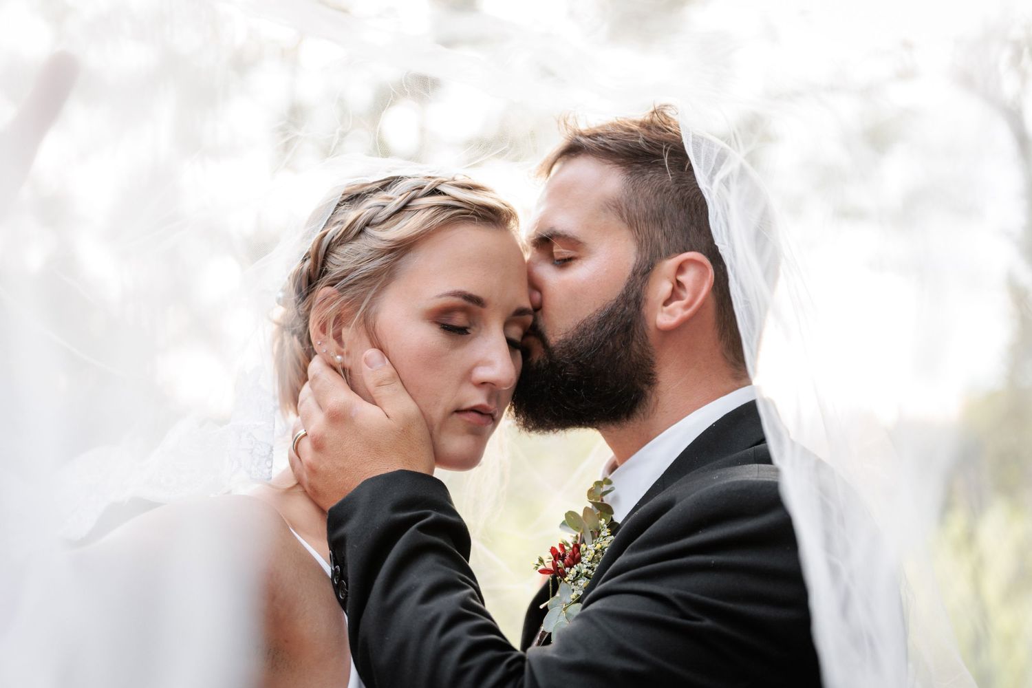 A couple shares an intimate moment during their outdoor wedding ceremony with a dreamy, soft-focus background.