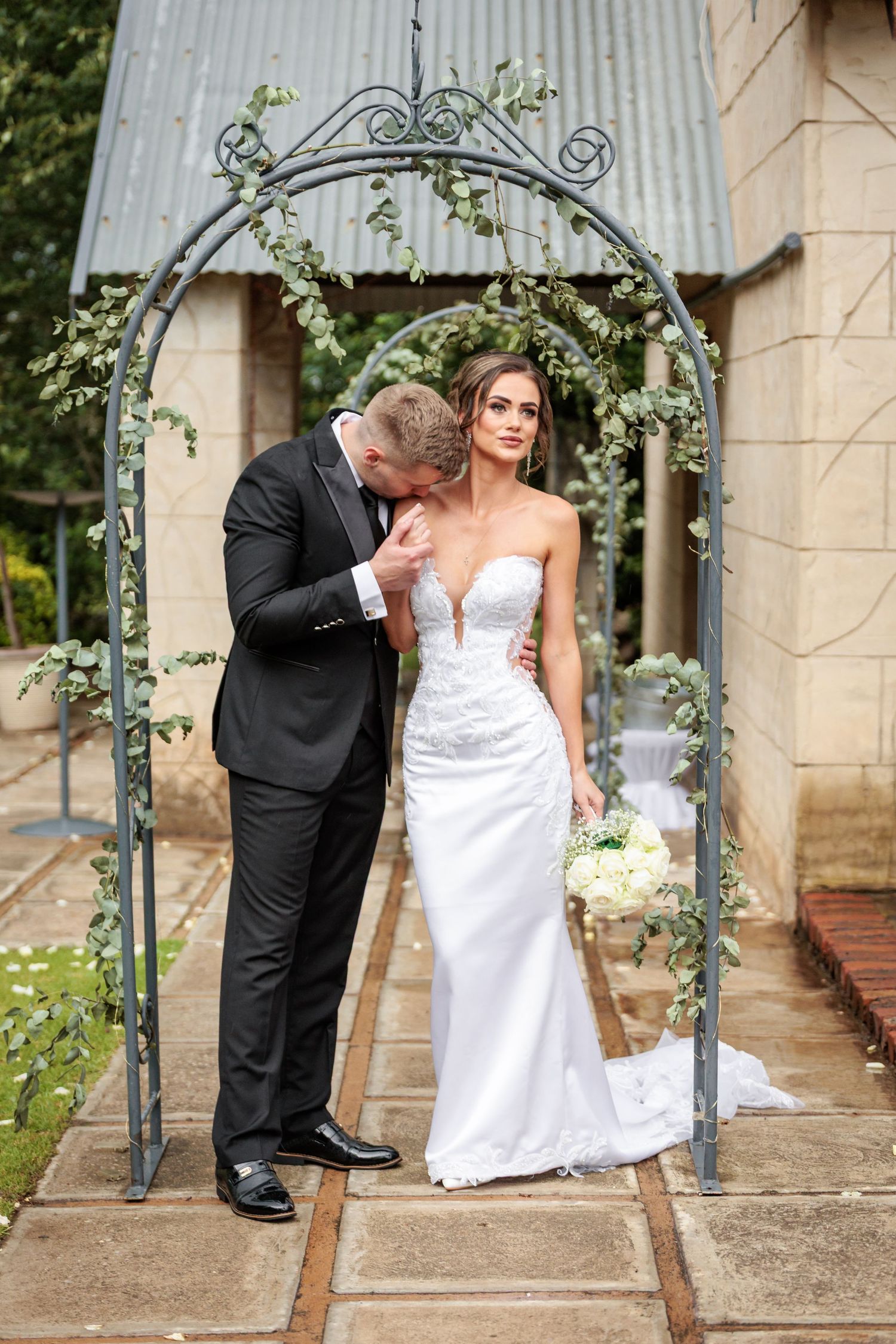 A romantic wedding couple poses together under an outdoor archway in a series of artistic photos.