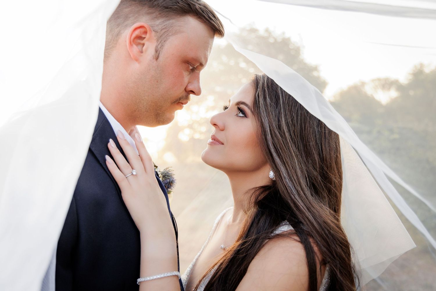 Intimate wedding couple portraits with flowing veil at sunset.
