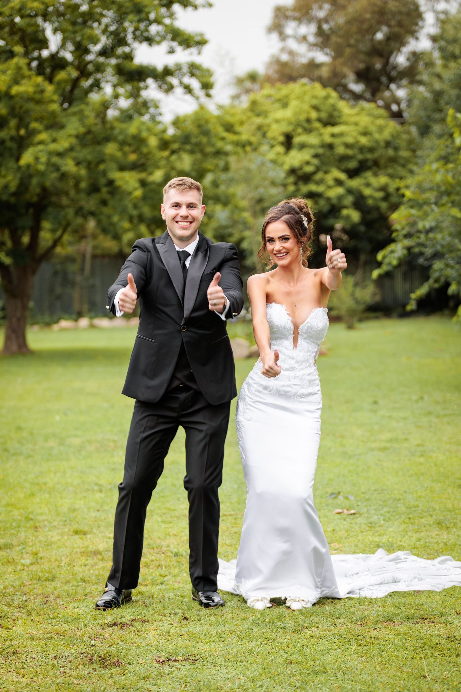 Newlyweds celebrate joyfully on a lush green lawn during their outdoor wedding ceremony.