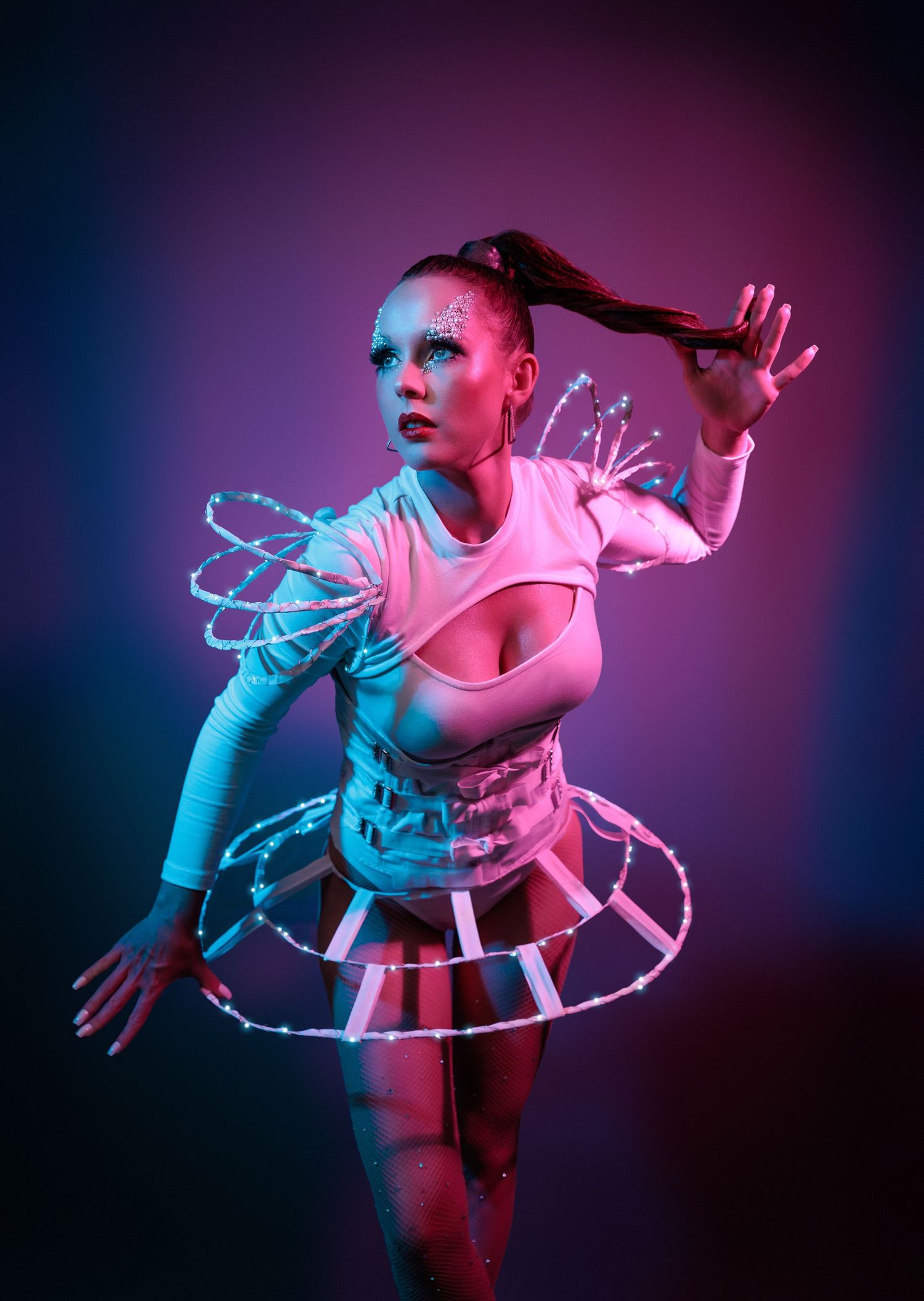 Dancer performs dynamic movements in colorful lighting with pink and blue hues creating a striking visual effect.