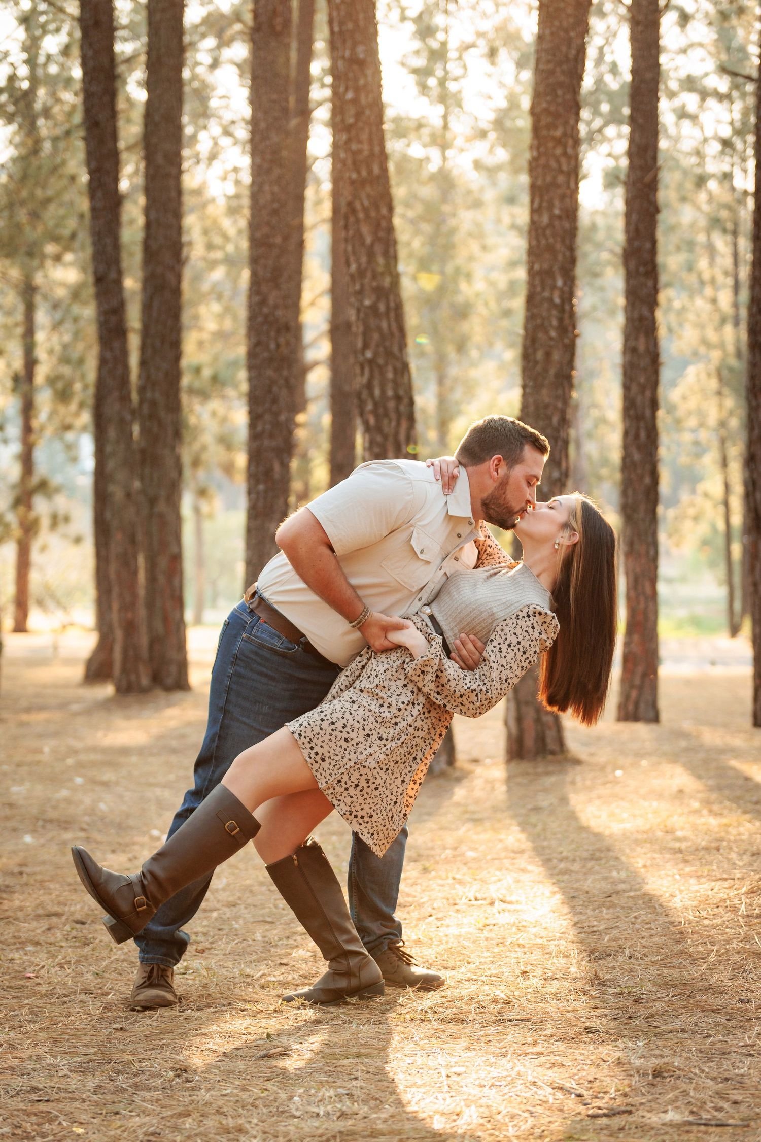 A romantic couple dances together in a sunlit pine forest during golden hour.