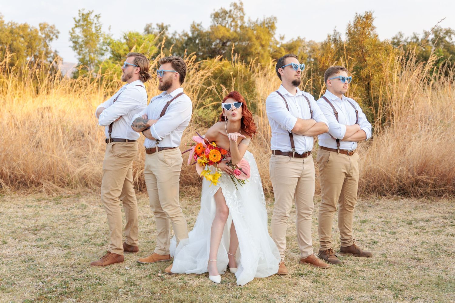 Wedding party having fun and posing in a rustic outdoor setting.