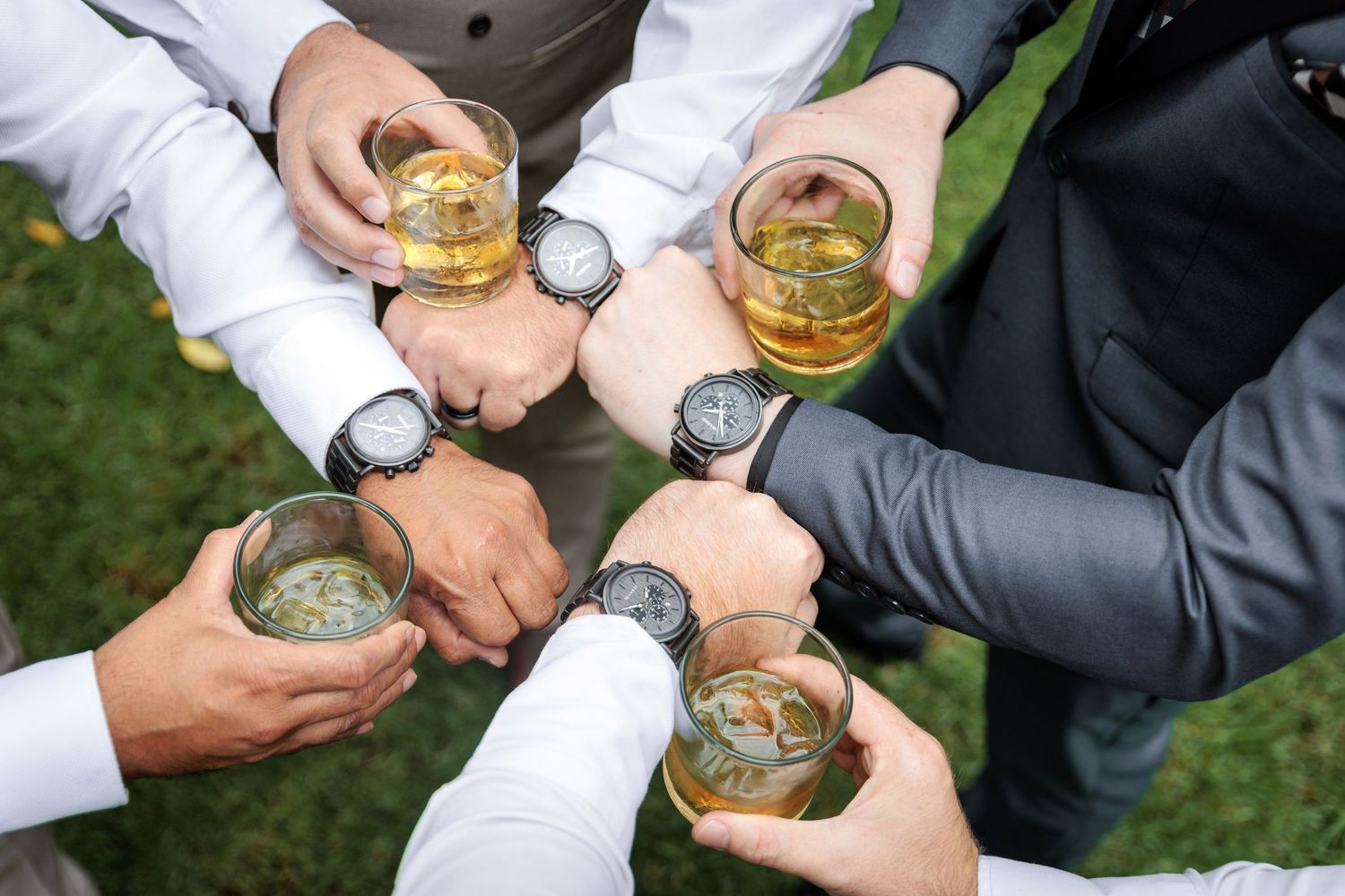 Groomsmen toasting with whiskey glasses during wedding celebration.