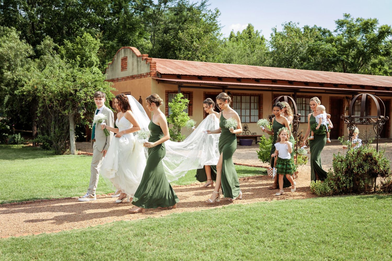 An outdoor wedding celebration with guests gathered on a lush green lawn.