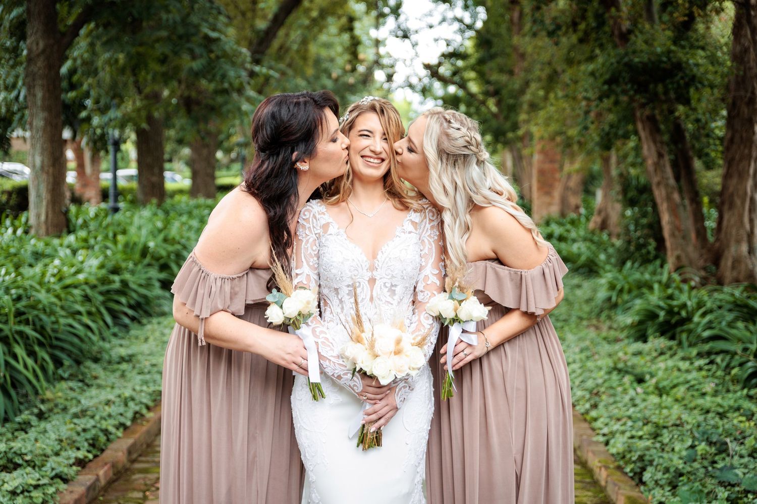 Wedding party wearing mauve dresses poses with bride in garden setting.