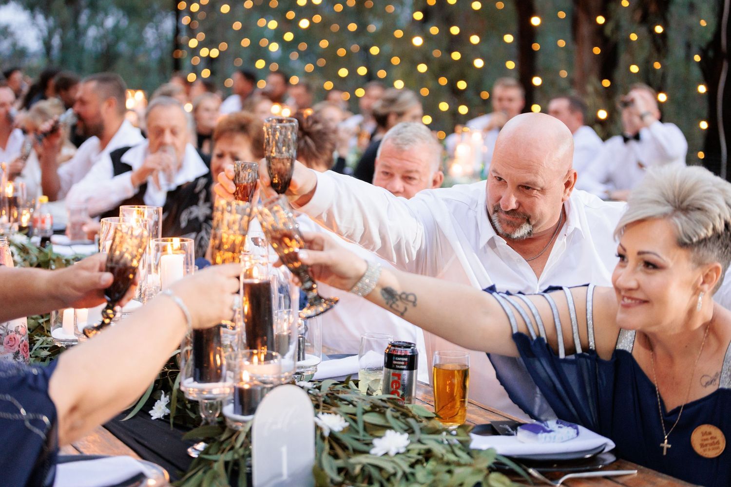 Wedding reception guests enjoying drinks and conversation at an outdoor evening celebration.