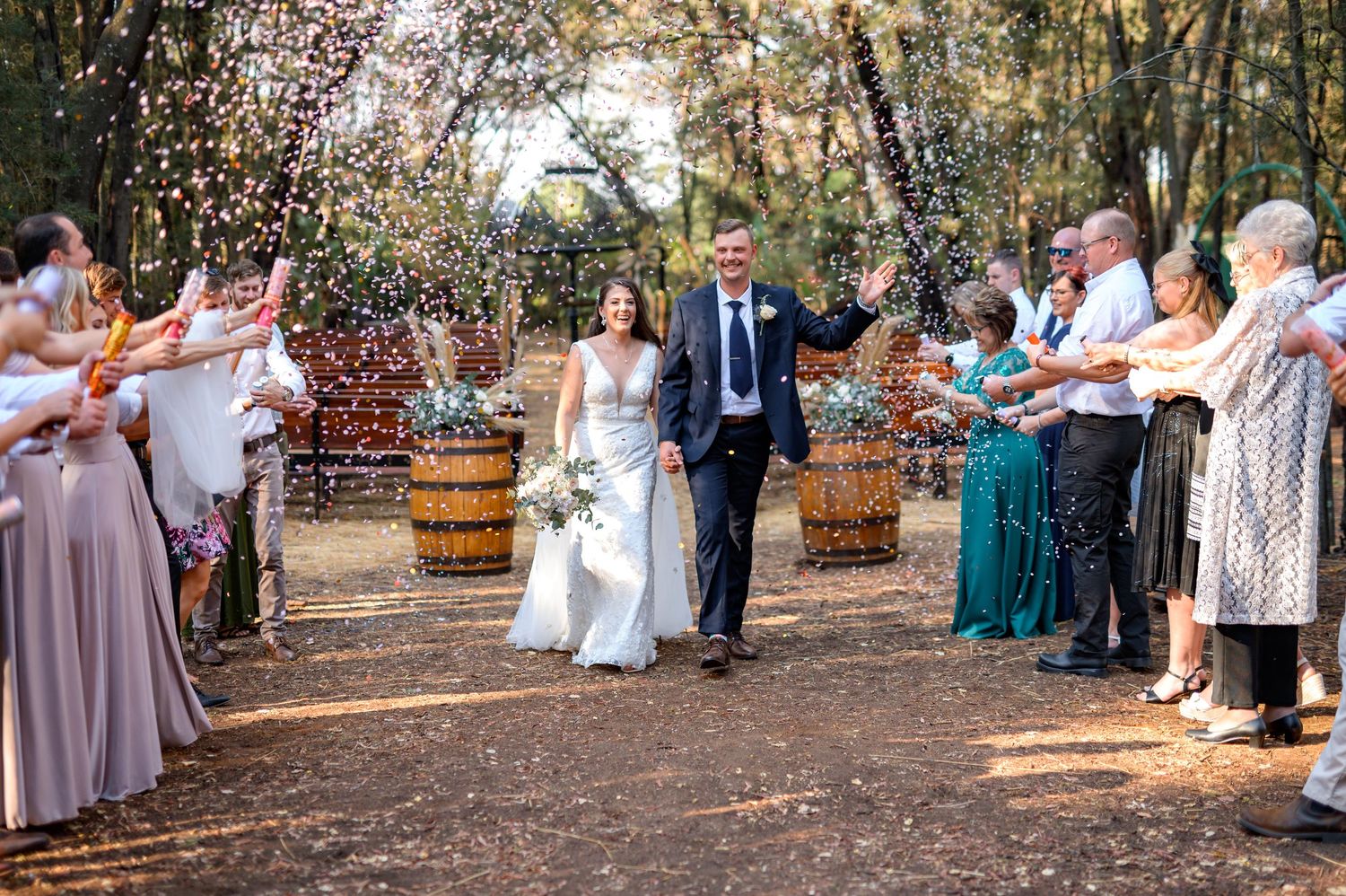 Wedding guests celebrate outdoors throwing confetti during a joyful moment.