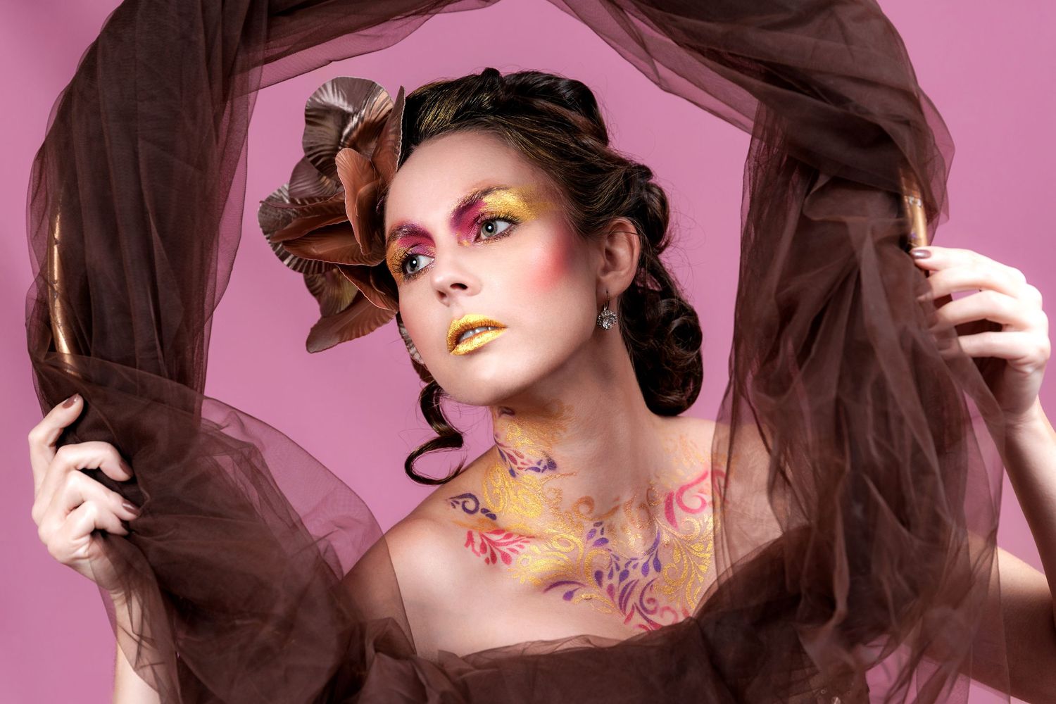 Creative fashion portrait with vibrant pink lighting and artistic makeup featuring colorful dots and patterns.