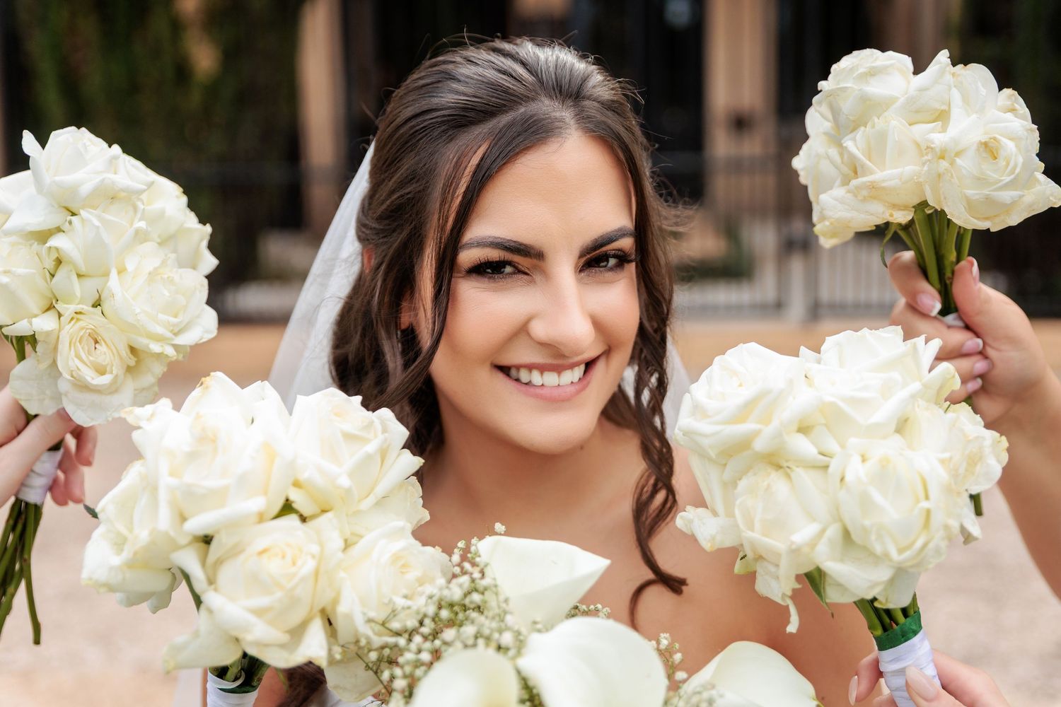 A bridal party poses with elegant white bouquets of peonies and roses in a formal wedding setting.