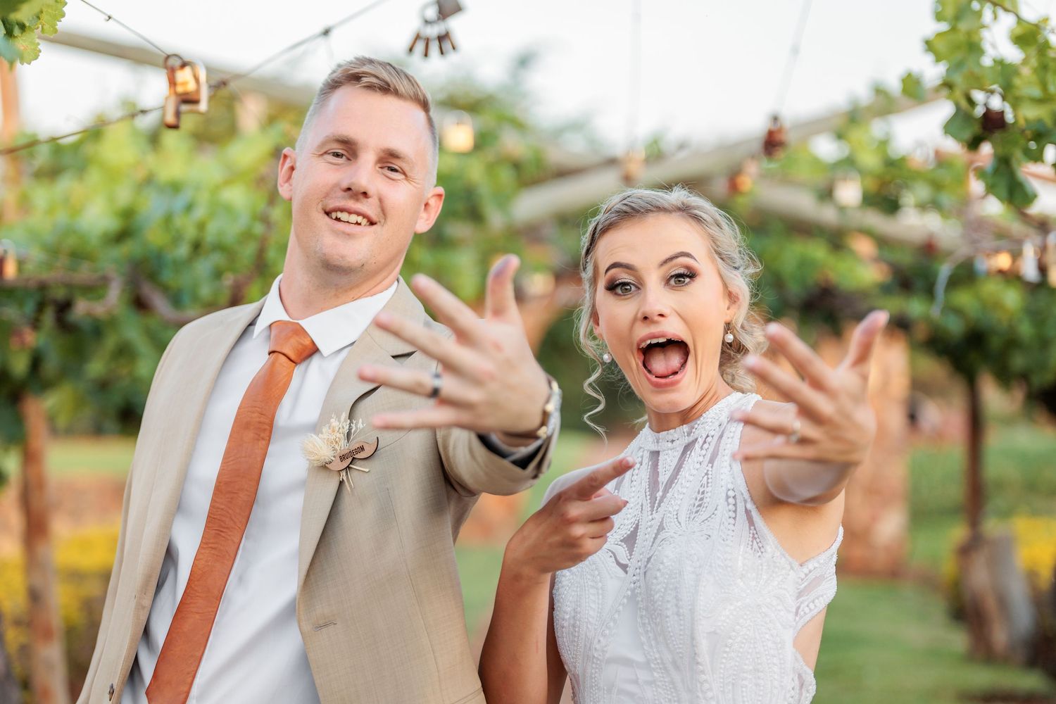 Playful wedding party celebrating in a lush vineyard setting.
