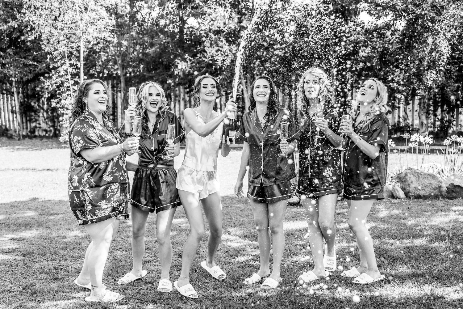 A group of people in formal attire pose together in a garden setting during a summer celebration.