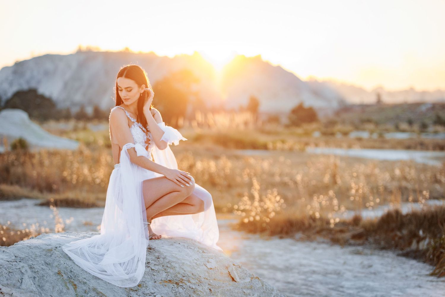 A person in a flowing white dress twirls gracefully in a desert landscape during golden hour.