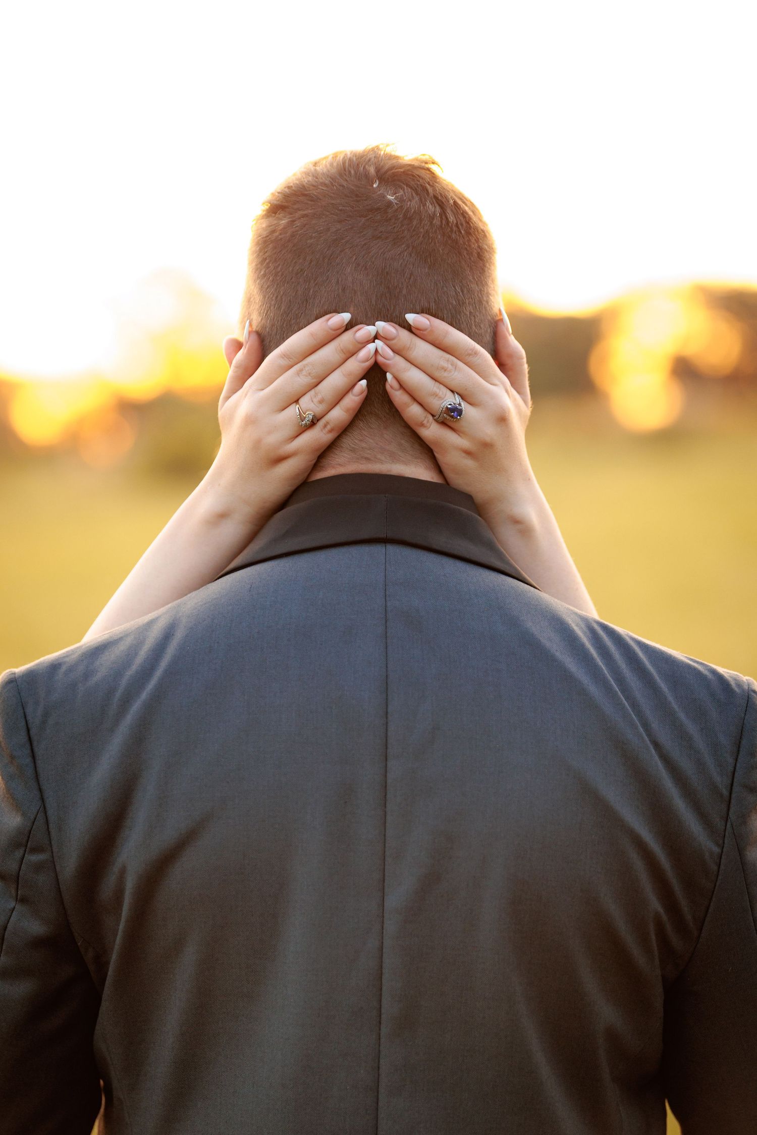 Back view of groom in dark suit during sunset golden hour photography.