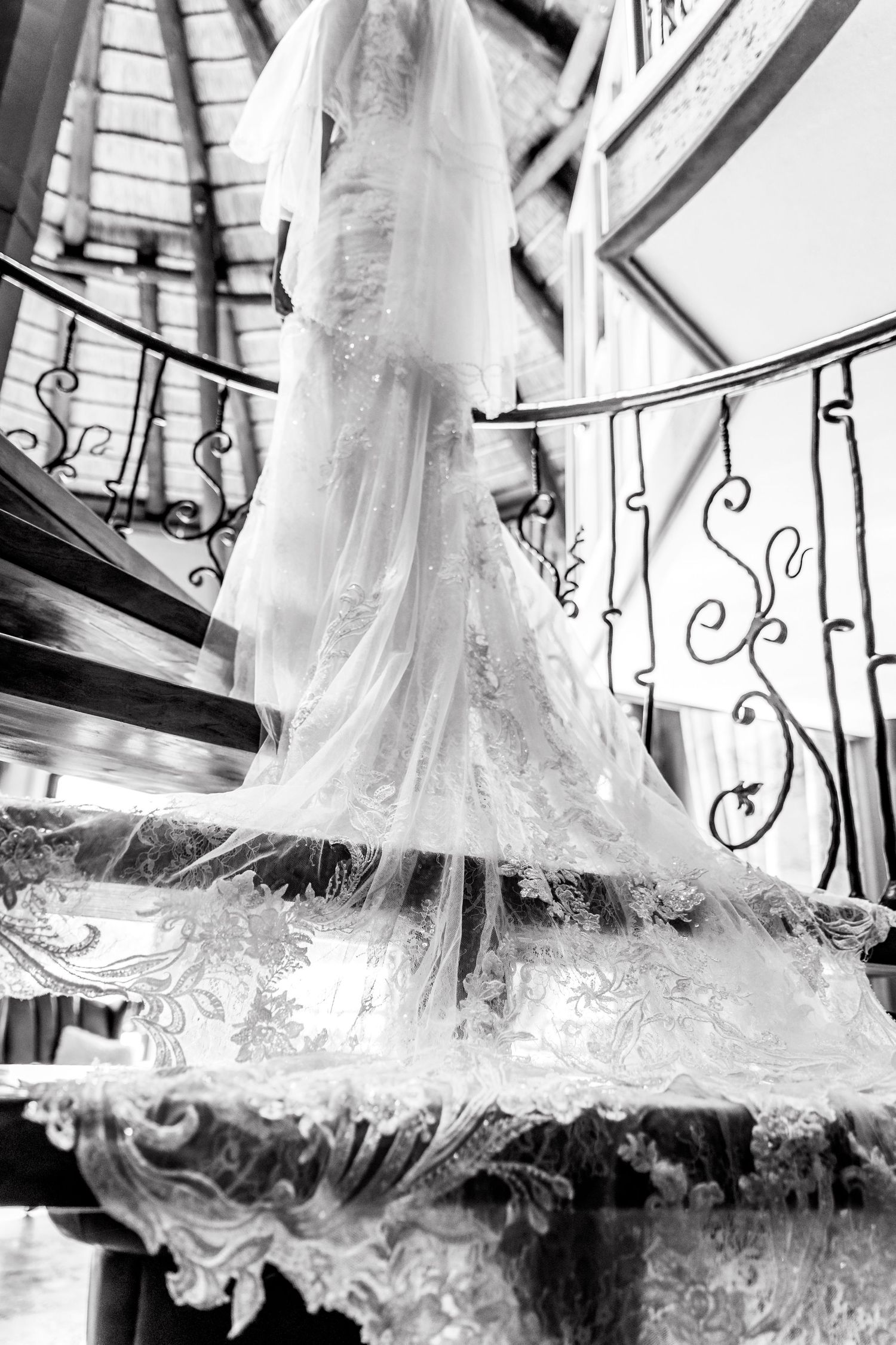 Elegant wedding dress train with intricate lace details photographed in black and white.