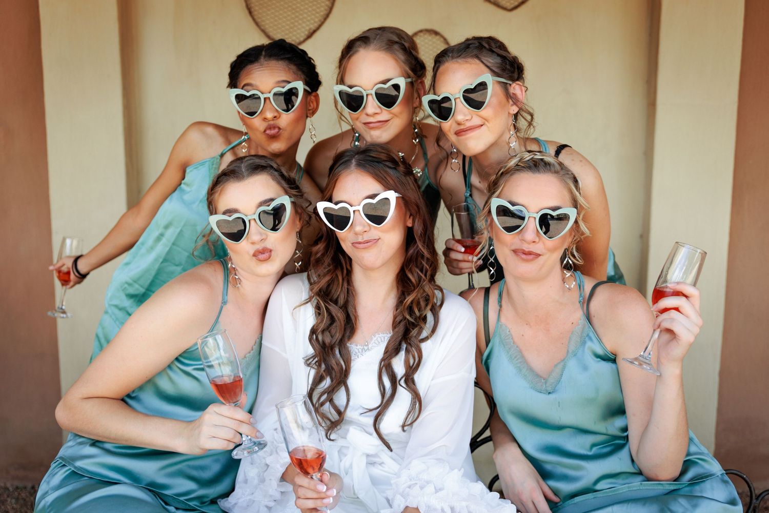 Wedding party wearing matching sunglasses and dresses posing together.
