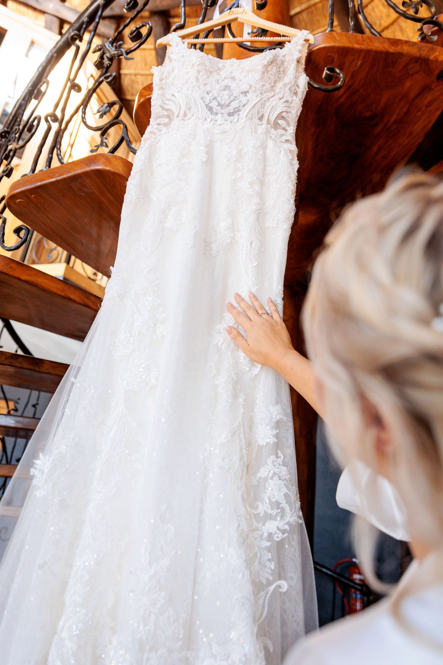 White lace wedding dress with intricate details hanging on display.