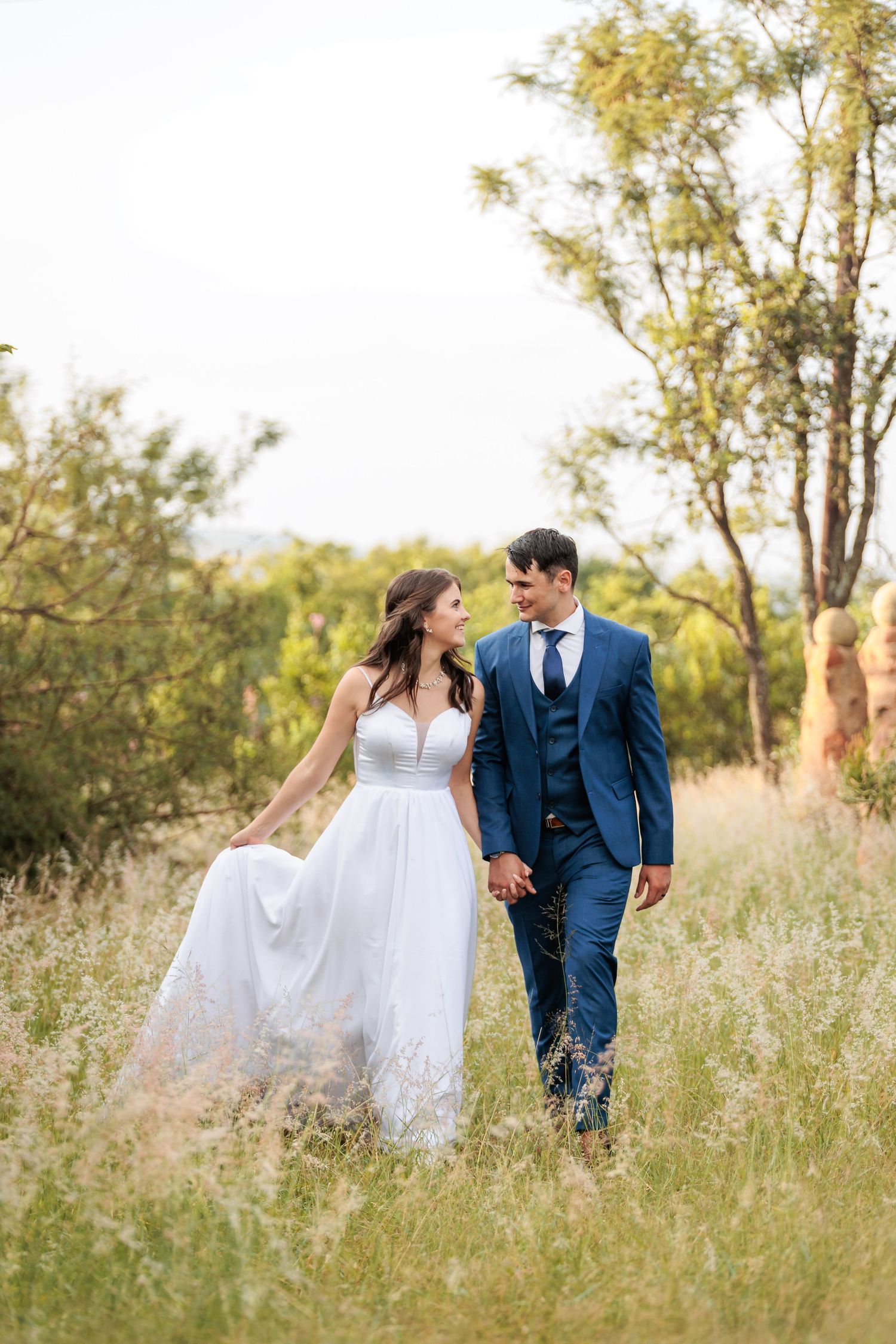 Romantic couple portraits in a meadow with soft golden light filtering through trees.