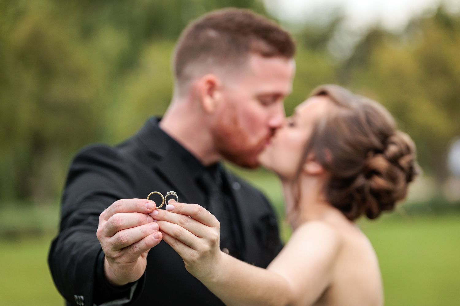 A romantic couple shares tender moments during an outdoor photo session in a lush green park setting.
