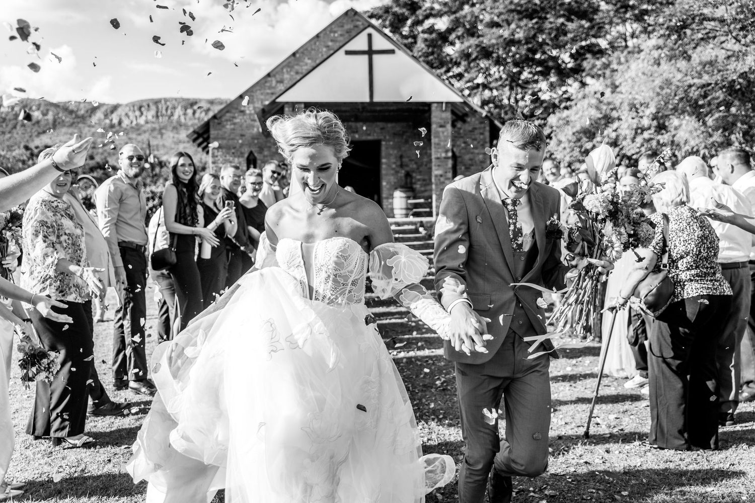 Black and white panoramic photo showing wedding guests celebrating outdoors during a summer celebration.