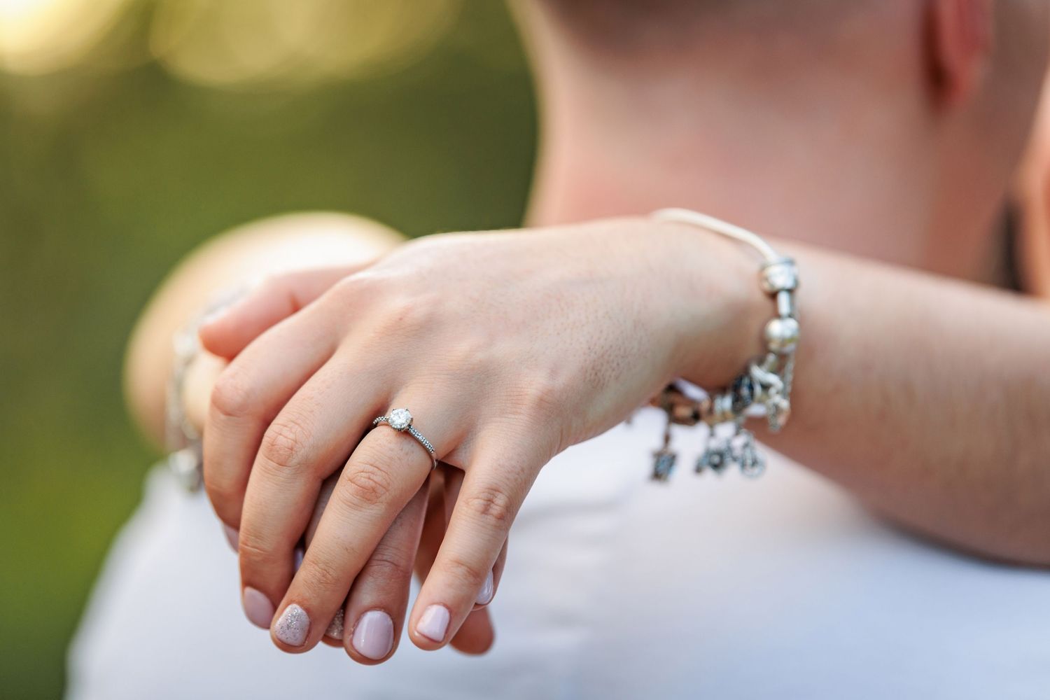 Close-up sequence of hands showing off a sparkling engagement ring in natural outdoor lighting.