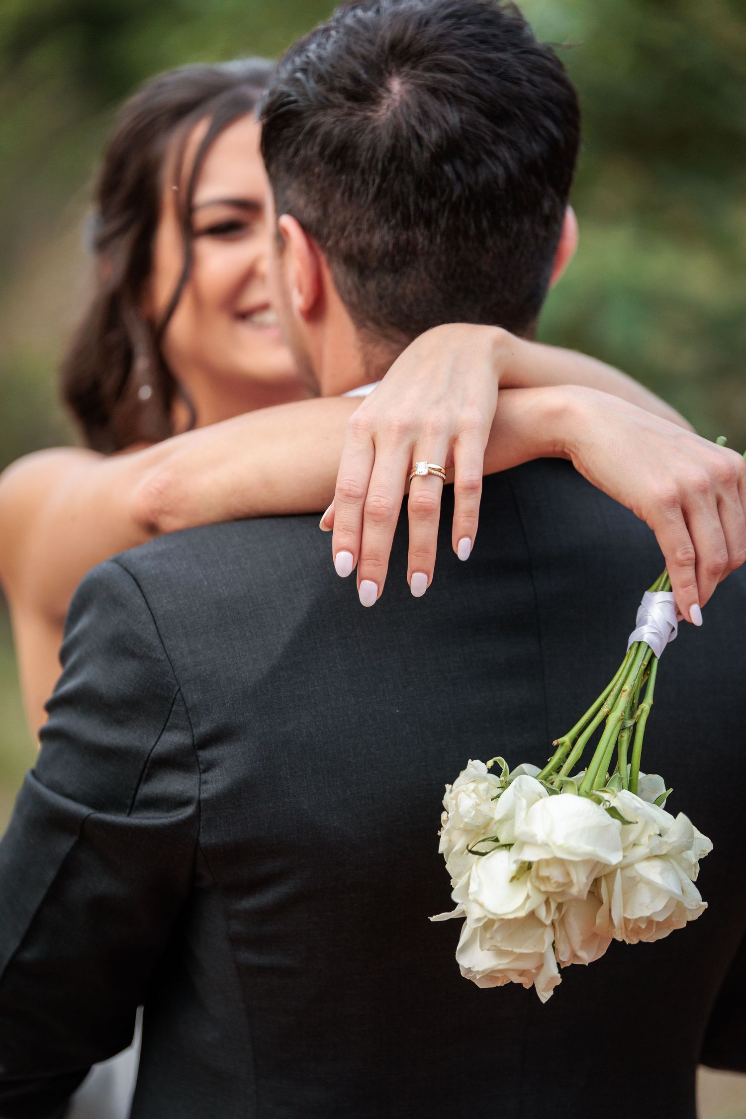 A romantic wedding photo series showing hands holding white roses while embracing in formal attire.