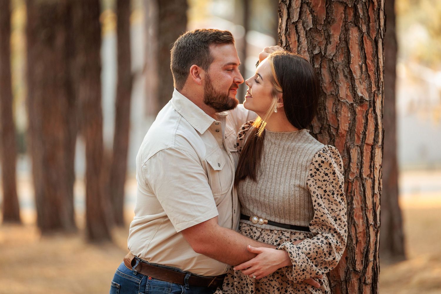 Romantic couple sharing intimate moments together in a pine forest at sunset.