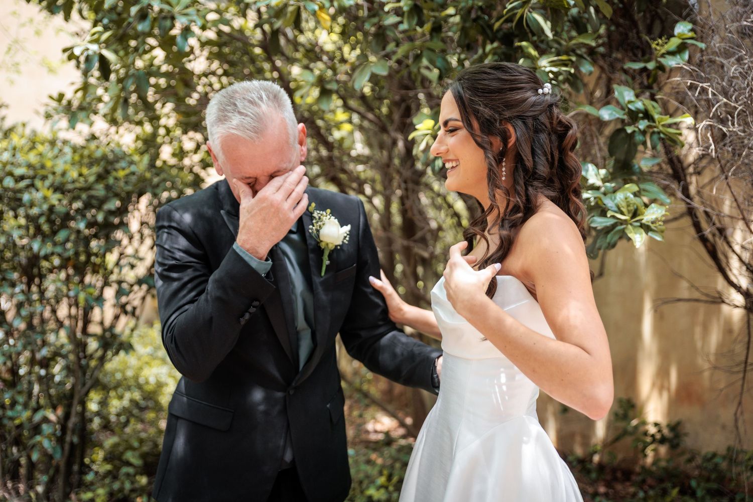 A romantic wedding couple shares an intimate moment in a garden setting with lush greenery and natural lighting.