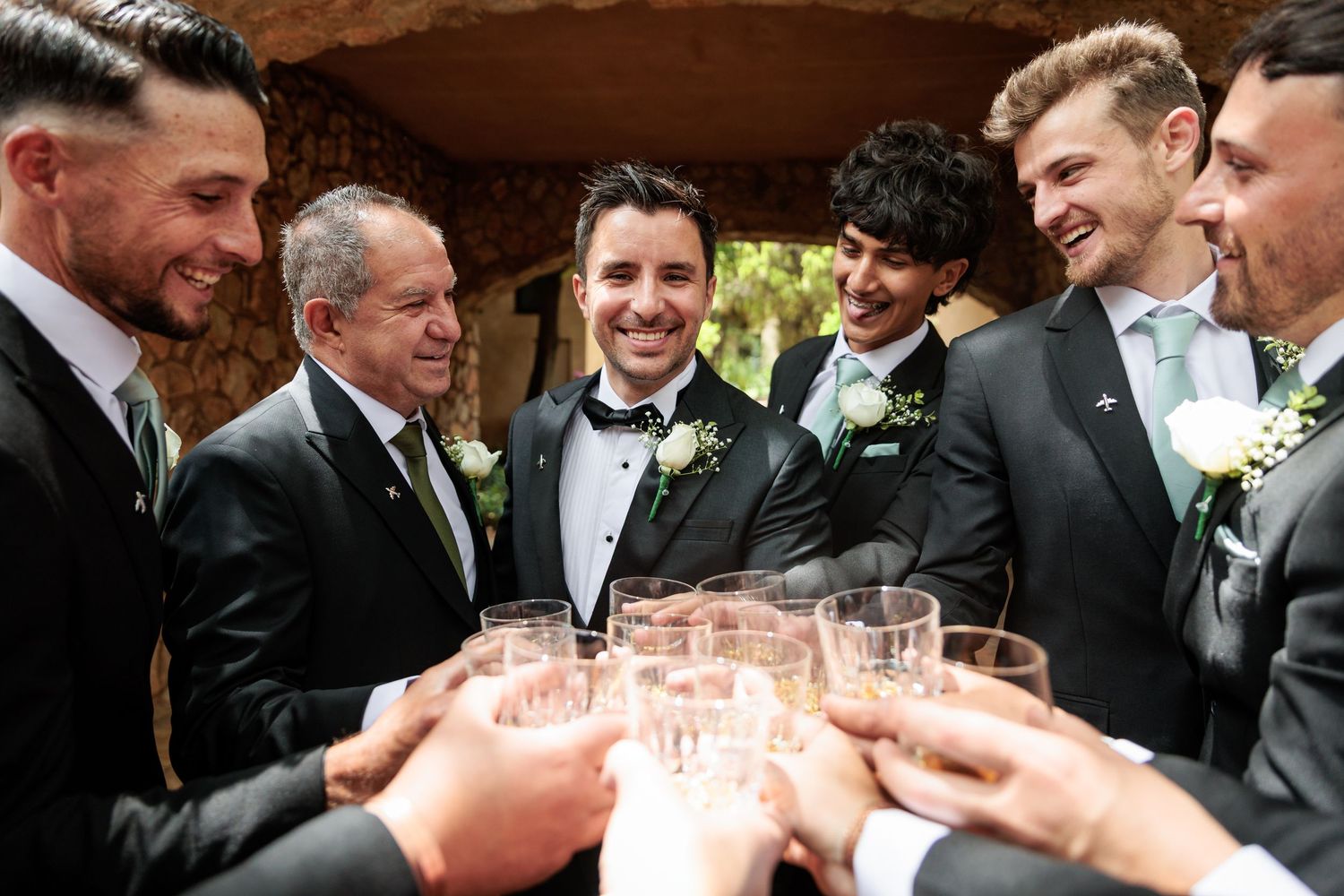 A group of men in formal attire toasting and clinking champagne glasses at a celebration.