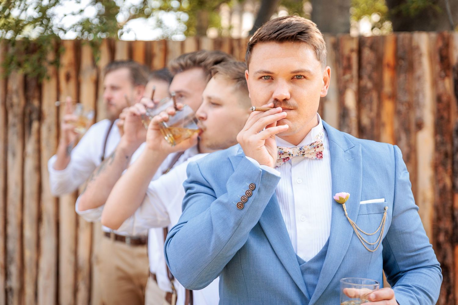Groomsmen in matching powder blue suits at an outdoor wedding venue.