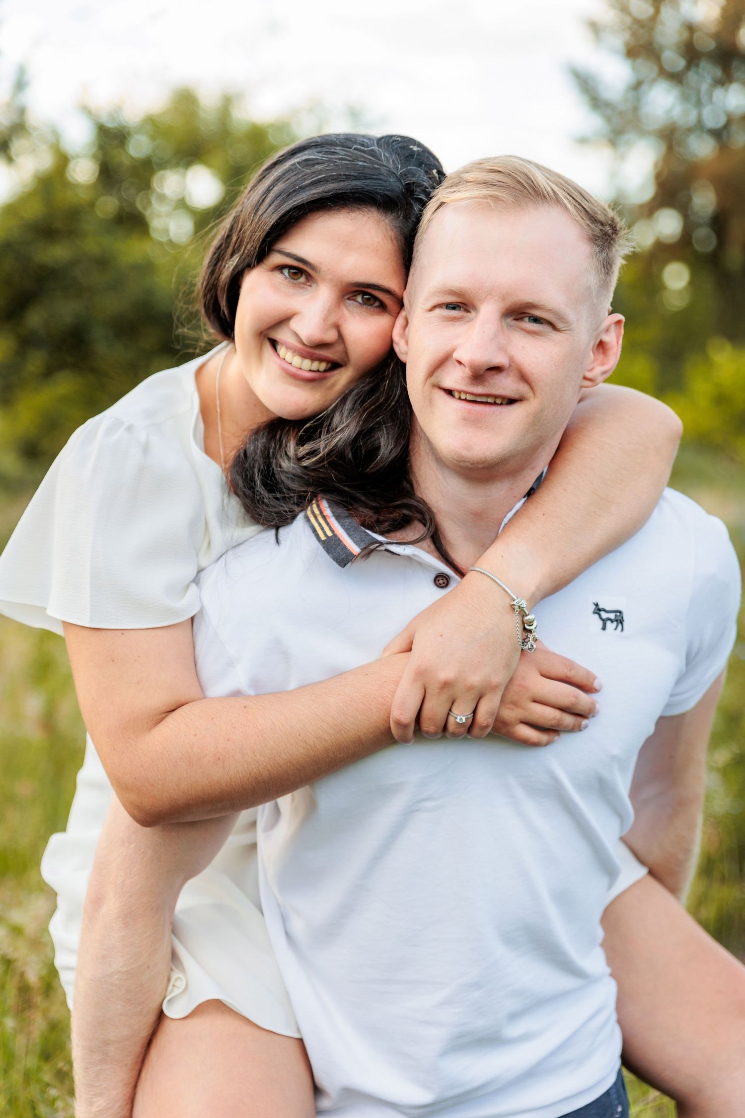 A couple in white shirts share playful and affectionate moments outdoors in a series of candid photos.