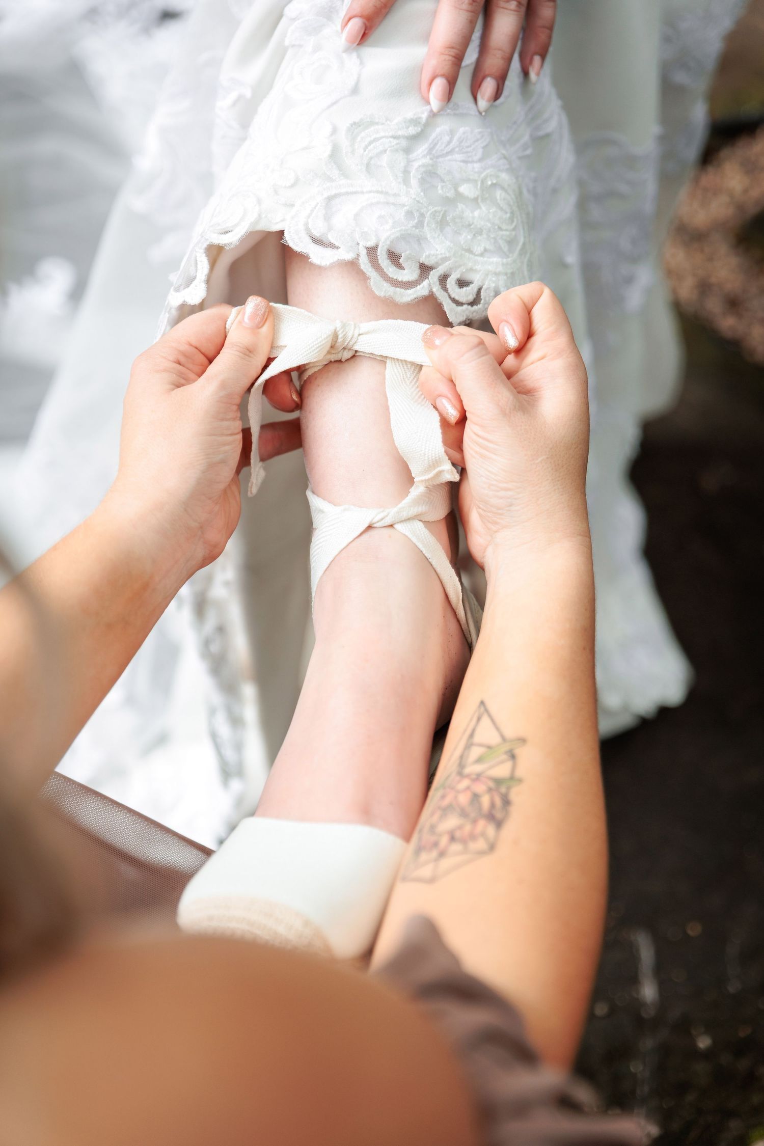 Close-up detail of delicate lace being adjusted on a white wedding dress.